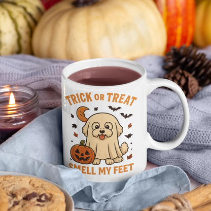 White ceramic Halloween mug with Bichon Frise ghost design and "Trick or Treat Smell My Feet" quote, surrounded by autumn decorations, pumpkins, pinecones, and cozy textures – perfect for fall gifting.