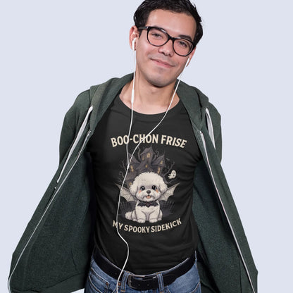 A mockup of a man wearing a black unisex t-shirt with a funny Halloween design for Bichon Frise dog lovers. The graphic features a cute Bichon Frise puppy with bat wings and the text "BOO-CHON FRISE MY SPOOKY SIDEKICK