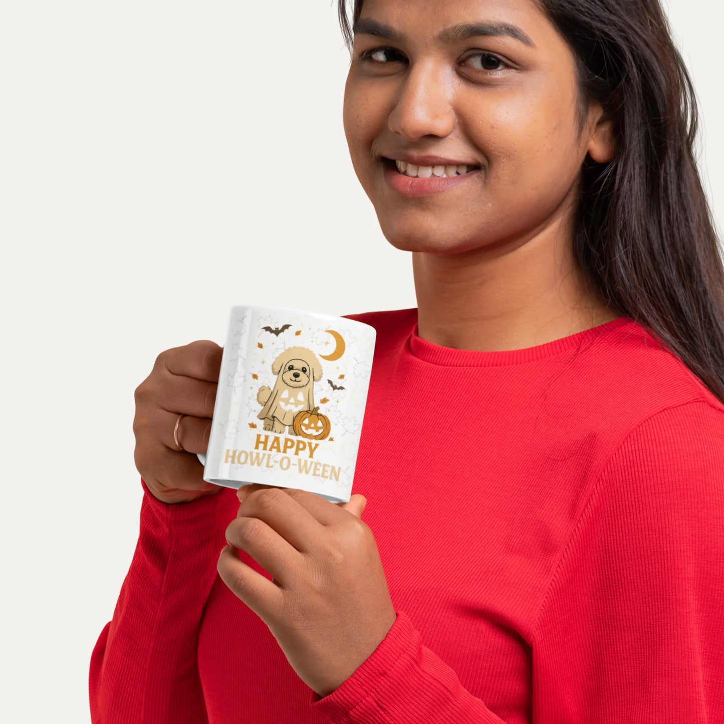Smiling woman in red shirt holding a white Halloween mug with a cute Bichon Frise ghost design and the text 'Happy Howl-o-Ween