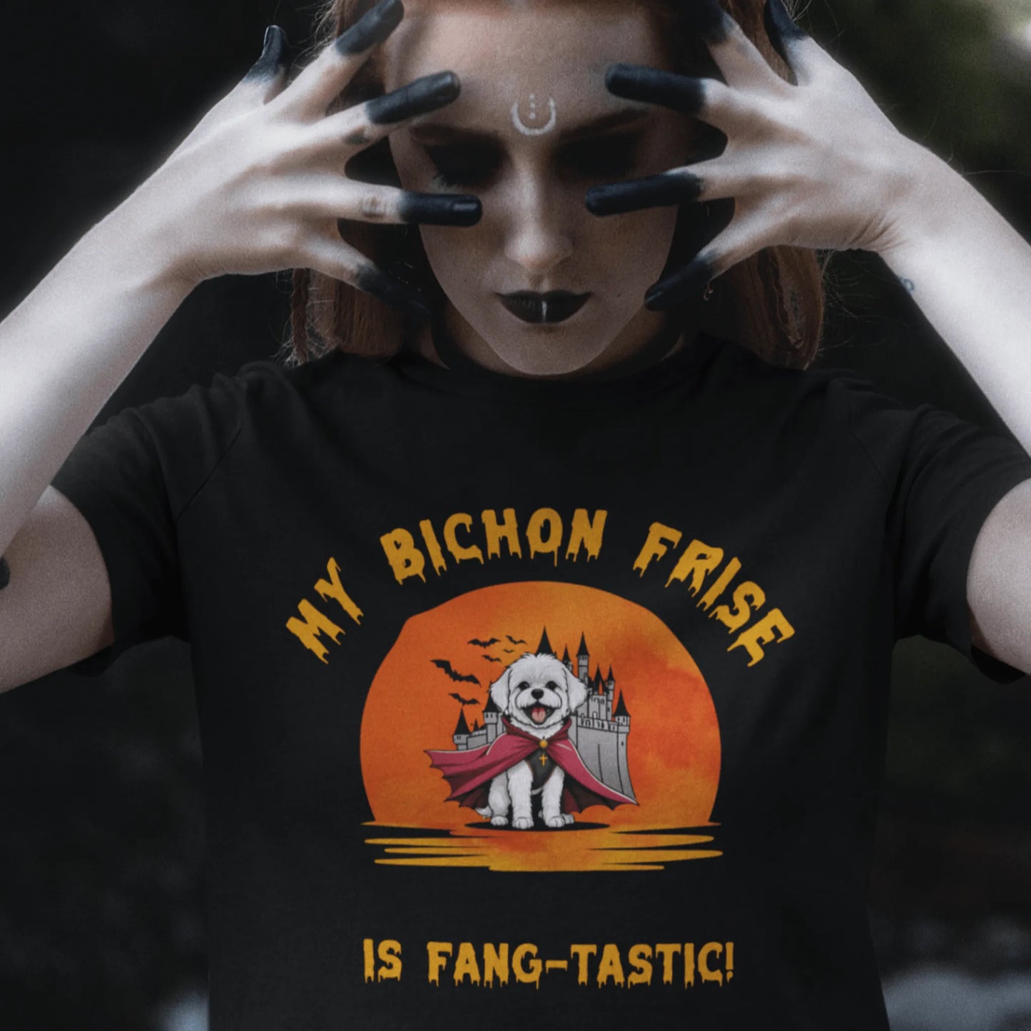 Woman in gothic makeup wearing a black Halloween T-shirt with a “My Bichon Frise is Fang-tastic!” design featuring a Bichon Frise dressed as a vampire in front of a spooky castle and full moon.